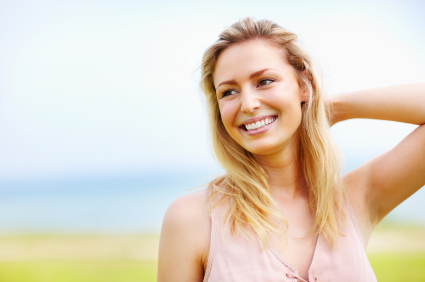 Frau mit blonden Haaren und rosa Top lächelt